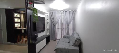 a living room with a couch and a television at Apto 5 Estrelas no Centro de Pelotas in Pelotas