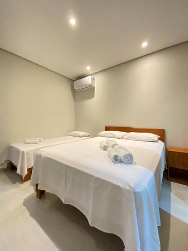 two beds with white sheets in a room at Villa Licuri Boiçucanga in Boicucanga