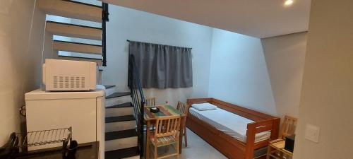 a small room with a bed and a refrigerator and a bunk bed at Villa Licuri Boiçucanga in Boicucanga