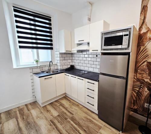 a kitchen with white cabinets and a stainless steel refrigerator at Elegante apartamento de diseño. in Almería