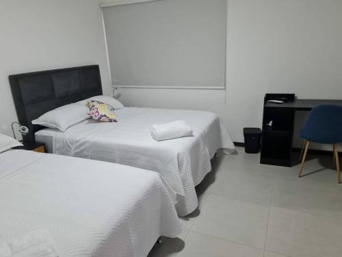 a bedroom with two beds and a desk and a blue chair at Departamento Familiar en Equipetrol in Santa Cruz de la Sierra