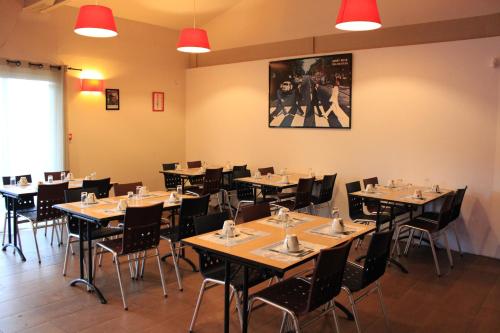 - un restaurant avec des tables et des chaises dans une salle dans l'établissement Enzo Hotels Loudeac By Kyriad Direct, à Loudéac