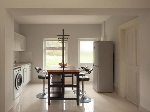 La cuisine est équipée d'une table, de chaises et d'un réfrigérateur. dans l'établissement Finn Farm Cottage, à Ballybofey