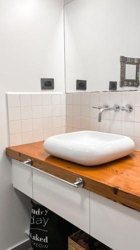 lavabo blanco en una encimera de madera en el baño en Casa Feliz en San Fernando del Valle de Catamarca
