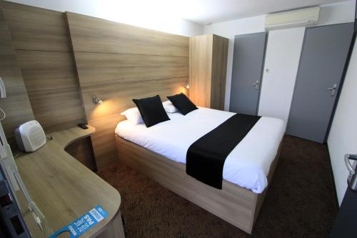 sypialnia z dużym białym łóżkiem z czarnymi poduszkami w obiekcie Enzo Hotels Loudeac By Kyriad Direct w mieście Loudéac