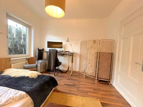 Un dormitorio con una cama y un escritorio y una ventana. en Dein Ankerplatz in Mülheim Ruhr - Traditionelle Zechenhaushälfte, en Mülheim an der Ruhr