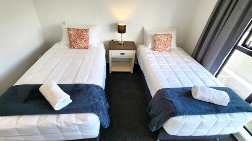 two twin beds in a room with a window at U Suites on Trieste Way in Paraparaumu