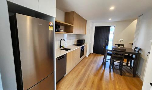 a kitchen with a table and a stainless steel refrigerator at U Suites on Trieste Way in Paraparaumu