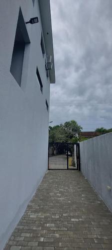 a white building with a gate and a brick sidewalk at Villa Licuri Boiçucanga in Boicucanga