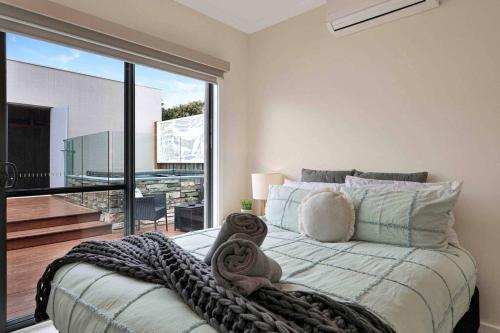 sypialnia z dużym łóżkiem i dużym oknem w obiekcie OG Spa Retreat- 3 bedroom, Spa, Central, Aircon w mieście Ocean Grove