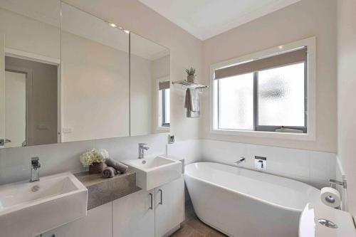 a bathroom with two sinks and a tub and a mirror at OG Spa Retreat- 3 bedroom, Spa, Central, Aircon in Ocean Grove
