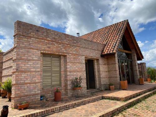 a brick house with a dog sitting in front of it at Cabaña campestre Villa Maria in Tuta