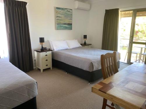 a bedroom with two beds and a table and a table sidx sidx sidx at Riverside Rest Nambucca Heads in Nambucca Heads