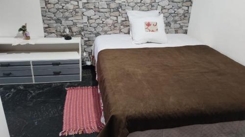 a bedroom with a bed and a stone wall at LO DE ROCCO in Esquel