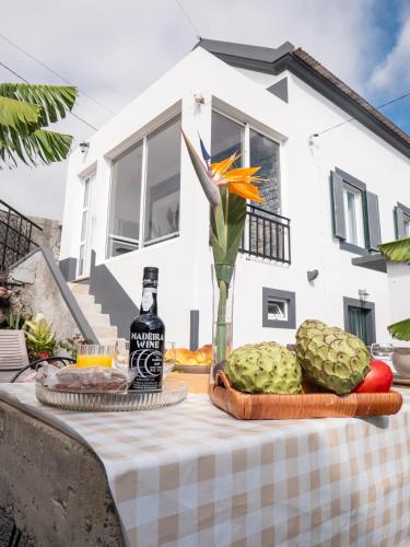 a table with a bottle of wine and fruit on it at Isabela House in Ponta do Sol