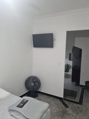 a bedroom with a tv on the wall and a chair at Hostel ANPRADO in Guarulhos