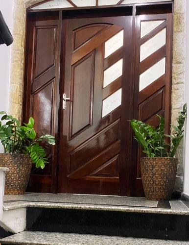 uma porta de madeira com dois vasos de plantas nos degraus em Hostel ANPRADO em Guarulhos