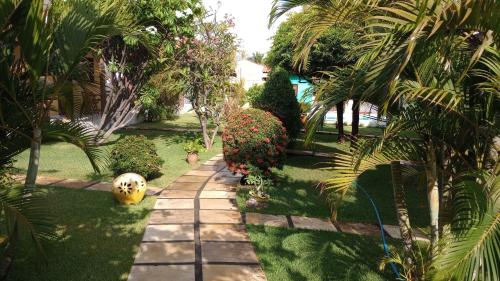 a garden with palm trees and a walkway at Chalés do Otto e Karine in Canoa Quebrada