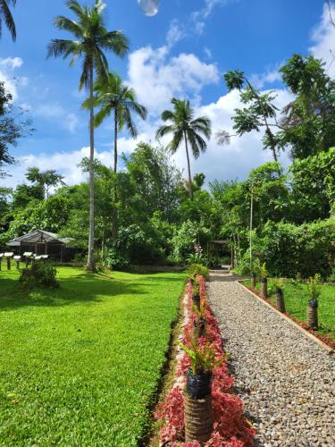 CROSSROADS HAVEN FARM في Majayjay: مسار تصطف فيه الزهور في حديقة بها أشجار النخيل