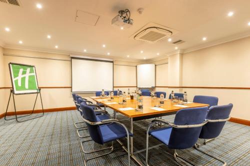 a conference room with a table and chairs and a screen at Holiday Inn - Glasgow Airport by IHG in Paisley