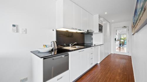 a kitchen with white cabinets and a sink at Sea Side 104 in Mandurah