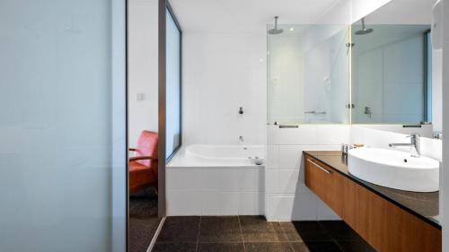 a bathroom with a sink and a tub and a mirror at Sea Side 104 in Mandurah