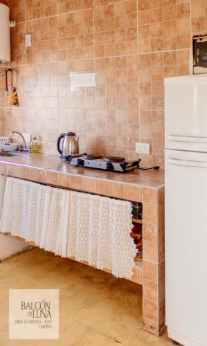 a kitchen with a counter with a stove and a refrigerator at Cabañas Balcon de Luna in El Carmen