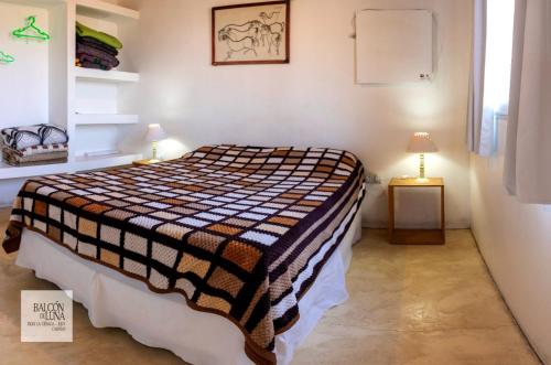 a bedroom with a bed with a checkered blanket at Cabañas Balcon de Luna in El Carmen