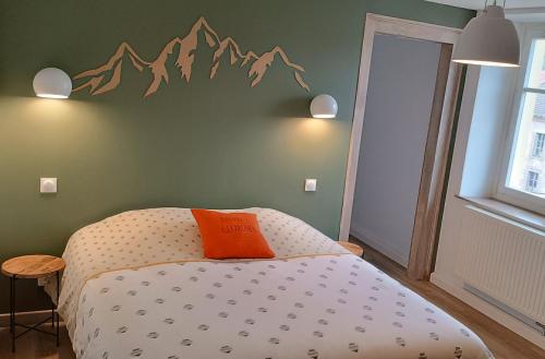 - un lit avec un oreiller orange sur un mur vert dans l'établissement Le Nesdel, à Gérardmer