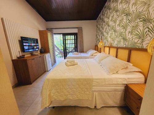 sypialnia z 2 łóżkami i telewizorem z płaskim ekranem w obiekcie GP05 - Chalé em pousada a 300m da Praia do Amor w mieście Pipa