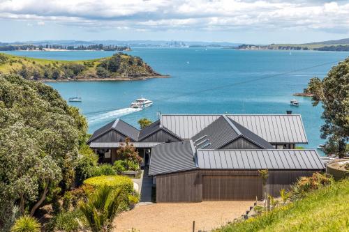 a house on a hill with a view of the water at The Moorings Studio Apartments in Oneroa