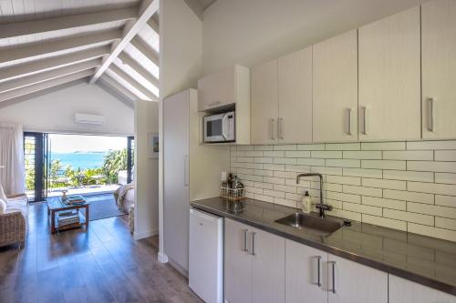 a kitchen with white cabinets and a view of the ocean at The Moorings Studio Apartments - Be My Guest Waiheke in Oneroa