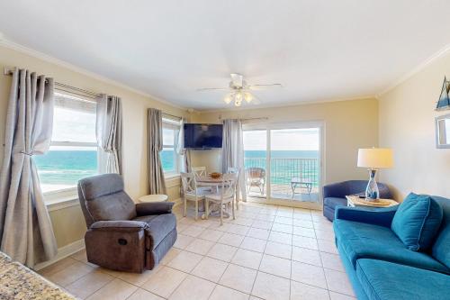 a living room with a blue couch and a table and chairs at Tradewinds 501 in Orange Beach