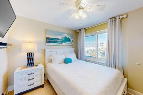 a bedroom with a bed with a ceiling fan and a window at Tradewinds 501 in Orange Beach