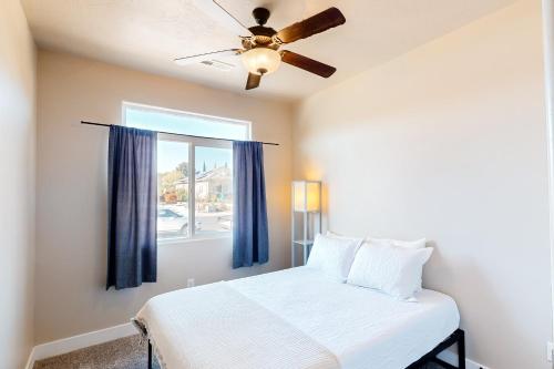 a bedroom with a bed with a ceiling fan and a window at Zion House in La Verkin