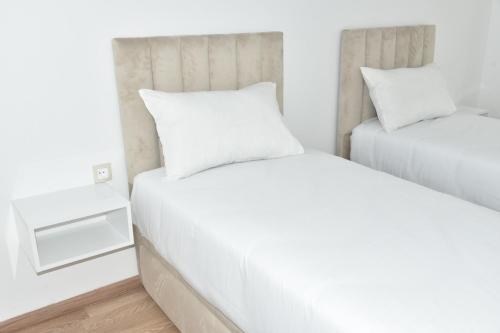um quarto com 2 camas e lençóis brancos em Lovely Apartment With Pool & Gym em Kenitra