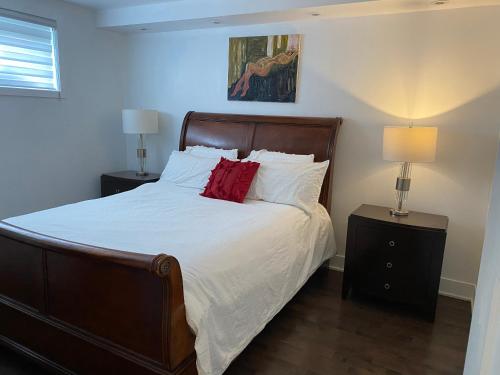 een slaapkamer met een bed met witte lakens en rode kussens bij Beautiful private full condo in Brossard
