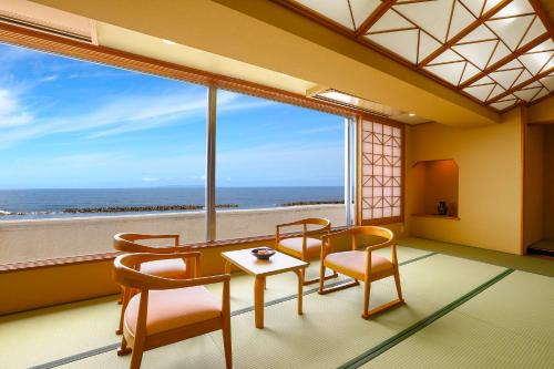 a room with a table and chairs and a large window at Ooedo Onsen Monogatari Premium Shiomiso in Murakami
