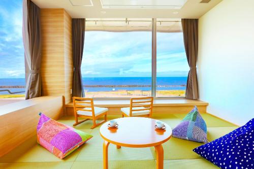 Zimmer mit einem Tisch und Stühlen sowie Meerblick in der Unterkunft Ooedo Onsen Monogatari Premium Shiomiso in Murakami