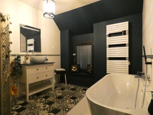 La salle de bains est pourvue d'une grande baignoire et d'un lavabo. dans l'établissement Élégante Chambre Rétro-Chic avec Lit King-Size proche commerces et autoroute A10 - FR-1-581-112, à Janville