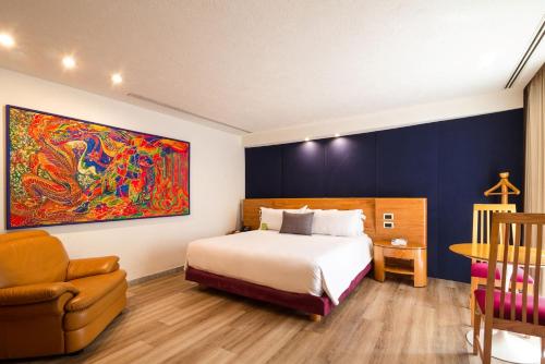 a bedroom with a bed and a painting on the wall at Camino Real Guadalajara in Guadalajara