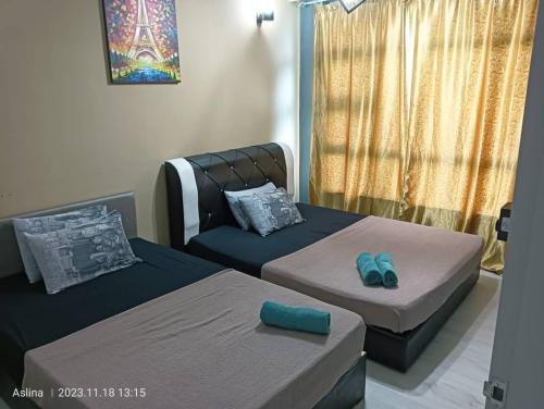 a room with two beds and a chair with slippers at Jesselton Quay Rashzia Kota kinabalu in Kota Kinabalu