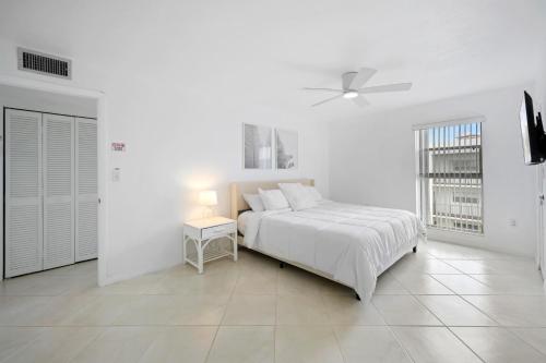 um quarto branco com uma cama e uma ventoinha de tecto em Sunny Isles Ocean Paradise em Sunny Isles Beach