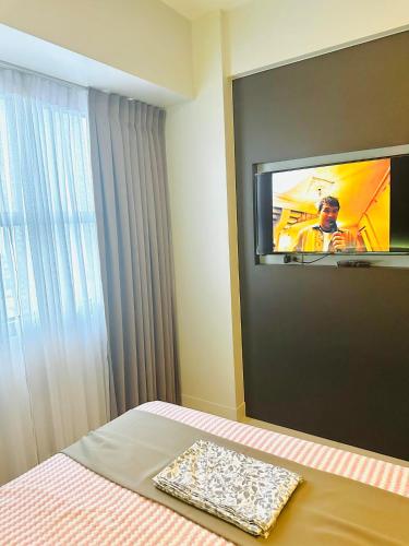 a bedroom with a tv on the wall and a bed at 41st Floor Horizons 101 Condo in Cebu City