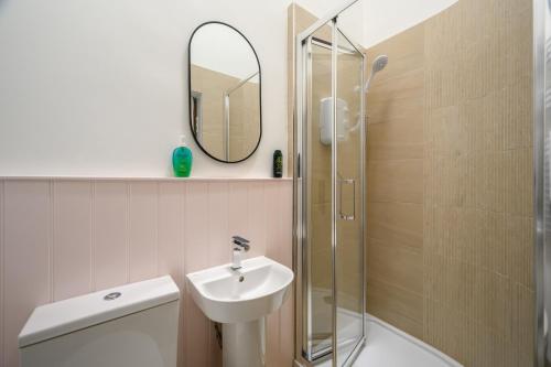 a bathroom with a sink and a shower with a mirror at 5-BR 3-BTH Newington Apartment - Modern & Spacious in Edinburgh