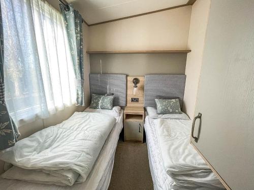 2 Betten in einem kleinen Zimmer mit Fenster in der Unterkunft Beautiful Caravan At Manor Park Nearby Hunstanton Beach Ref 23030w in Hunstanton