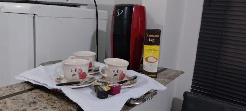 una mesa con tres tazas de té y platillos en ella en Casa próxima ao centro! en Uberaba