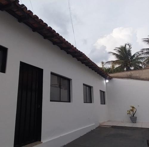 uma casa branca com uma porta preta e uma palmeira em Casa próxima ao centro! em Uberaba
