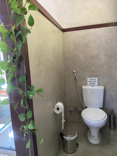 a bathroom with a toilet with a plant next to it at Matha Pousada e Bistrô in Lumiar