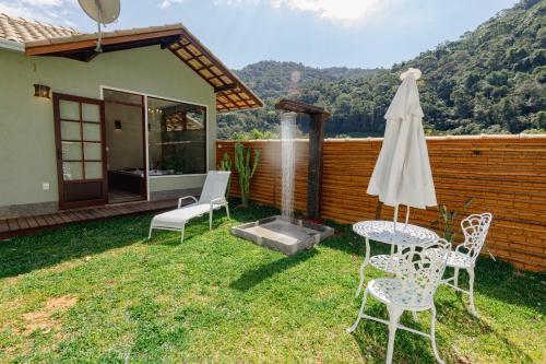 a patio with chairs and a table and an umbrella at Matha Pousada e Bistrô in Lumiar